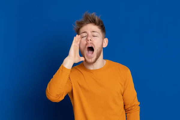 Aantrekkelijke Jongeman Met Een Geel Shirt Een Blauwe Achtergrond — Stockfoto