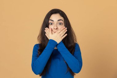 Sarı arka planda mavi forma giyen esmer genç kız.