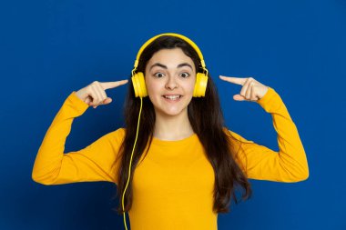 Esmer genç kız mavi arka planda sarı forma giyiyor.