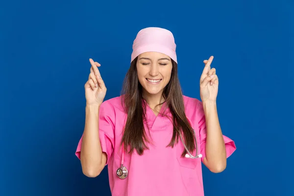 穿着蓝色背景粉红制服的年轻医生 — 图库照片