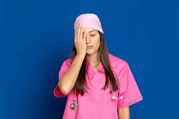 穿着蓝色背景粉红制服的年轻医生 — 图库照片