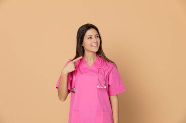 Sarı arka planda pembe üniformalı genç bir doktor.