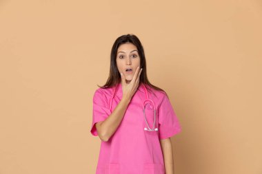 Sarı arka planda pembe üniformalı genç bir doktor.