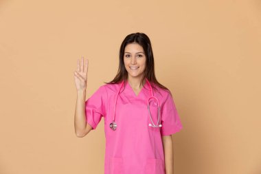 Sarı arka planda pembe üniformalı genç bir doktor.