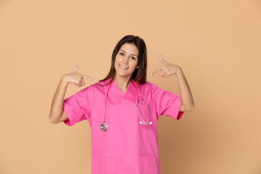 Sarı arka planda pembe üniformalı genç bir doktor.