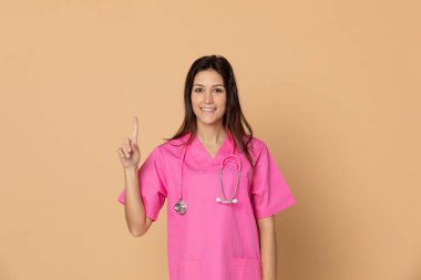 Sarı arka planda pembe üniformalı genç bir doktor.