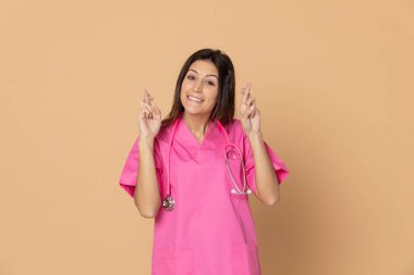 Sarı arka planda pembe üniformalı genç bir doktor.