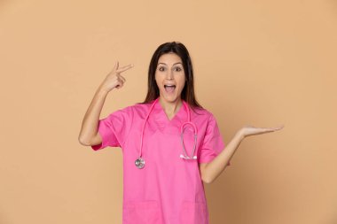 Sarı arka planda pembe üniformalı genç bir doktor.