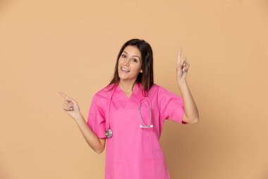 Sarı arka planda pembe üniformalı genç bir doktor.