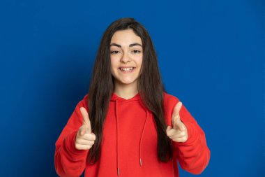 Esmer genç kız mavi arka planda kırmızı forma giyiyor.