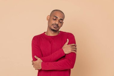 Sarı arka planda kırmızı formalı Afrikalı adam.