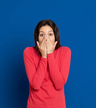 Esmer, mavi arka planda kırmızı tişört giyen genç bir kadın.