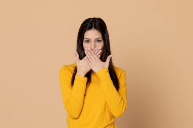 Sarı arka planda sarı tişört giyen esmer genç bir kadın.