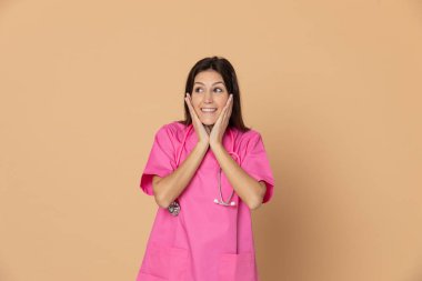 Mavi arka planda pembe üniformalı genç doktor.