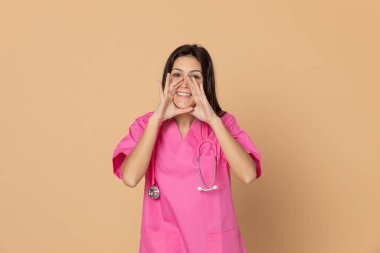 Mavi arka planda pembe üniformalı genç doktor.