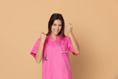 Mavi arka planda pembe üniformalı genç doktor.