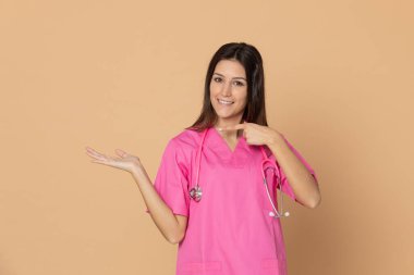 Mavi arka planda pembe üniformalı genç doktor.