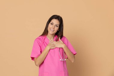 Mavi arka planda pembe üniformalı genç doktor.