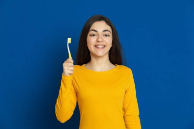 Esmer genç kız mavi arka planda sarı forma giyiyor.