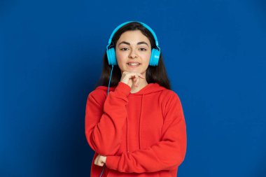 Esmer genç kız mavi arka planda kırmızı forma giyiyor.