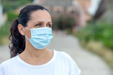 Sağlığını korumak için maske takan esmer kadın.
