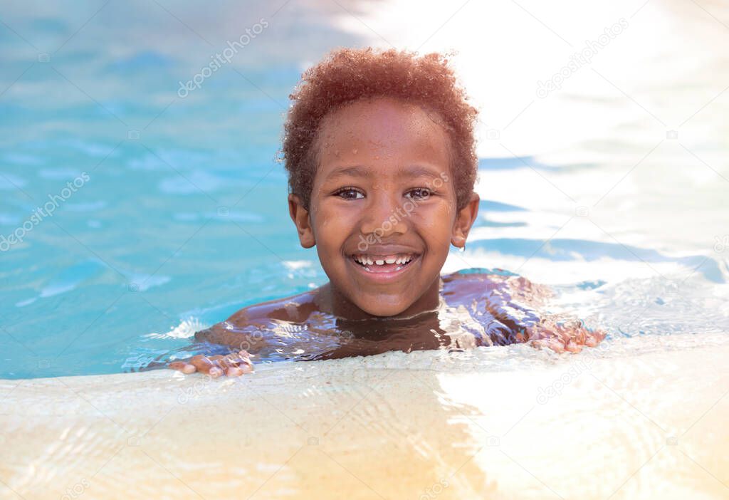 Little african child enjoying the summer in the pool 