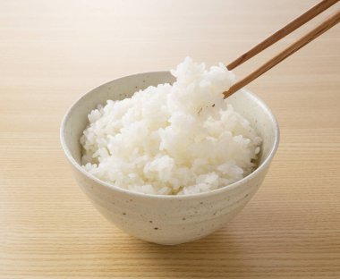 Ahşap arka planda çubuklarla pirinç kepçelerken çekilmiş yakın plan fotoğrafı.