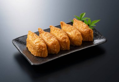 Siyah arka planda siyah bir tabakta Japon Inari Sushi 'si