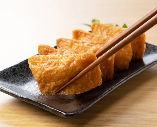 Japanse Inari Sushi Een Zwarte Plaat Tegen Een Houten Ondergrond — Stockfoto