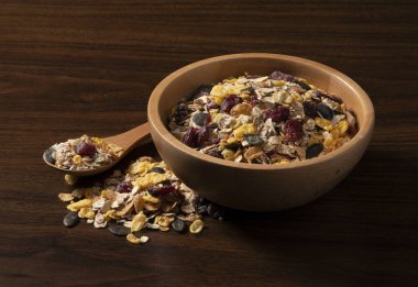 Tahta zemine dayalı bir kabın içindeki granola ve kaşık, bir açıdan fotoğraflanmış.