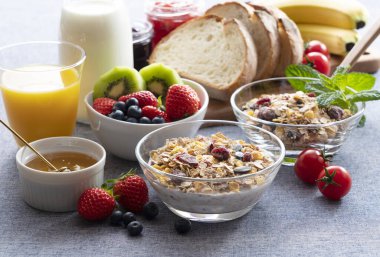 Images of a sumptuous breakfast of granola, bread, fruit and juice clipart