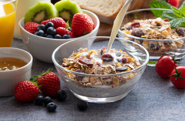 Image of a sumptuous breakfast of bread, fruit and juice. Close up of the scene where milk is poured over granola