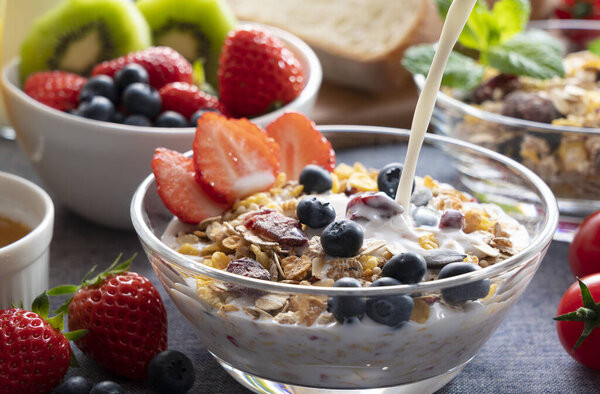 Image of a sumptuous breakfast of bread, fruit and juice. Close up of the scene where milk is poured over granola