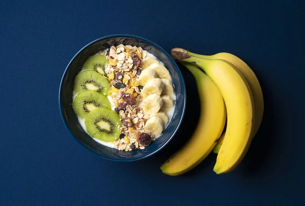 Owoce Granola Jogurt Podawane Pojemniku Ciemnoniebieskim Tle Obok Umieszczono Banana — Zdjęcie stockowe