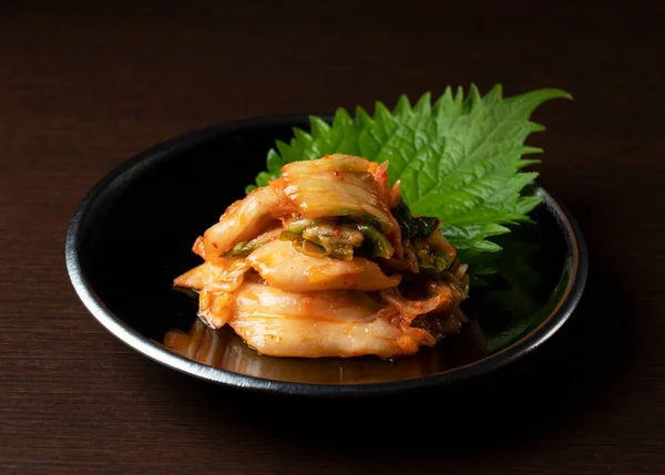 Kimchi Een Plaat Tegen Een Donkere Houten Ondergrond — Stockfoto