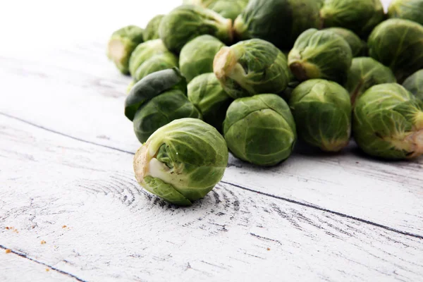 Many fresh brussel sprouts over white wooden texture — Stock Photo, Image