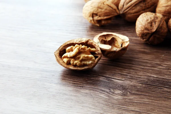 Ядра волоських горіхів і цілі волоські горіхи на коричневому дерев'яному столі — стокове фото