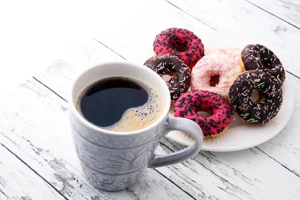 Пончики и кофе на сладкий завтрак на деревянном фоне — стоковое фото
