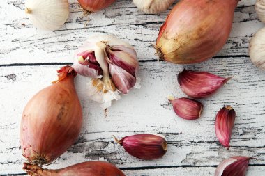 Beyaz ahşap zemin üzerinde birçok sarımsak ve soğan sebze