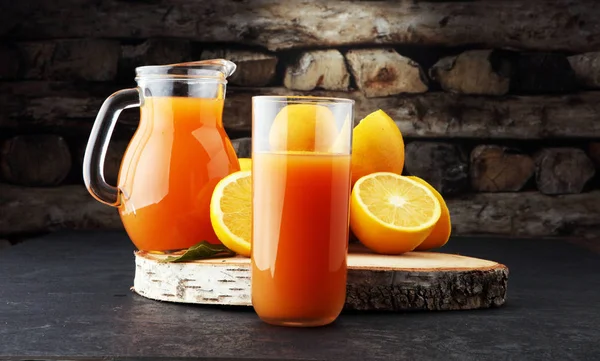 Glass jar of fresh orange juice with fresh fruits on dark table. — Stock Photo, Image