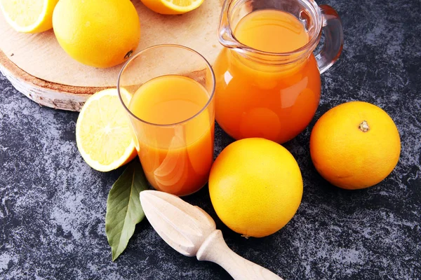 Glas mit frischem Orangensaft mit frischen Früchten auf dunklem Tisch. — Stockfoto