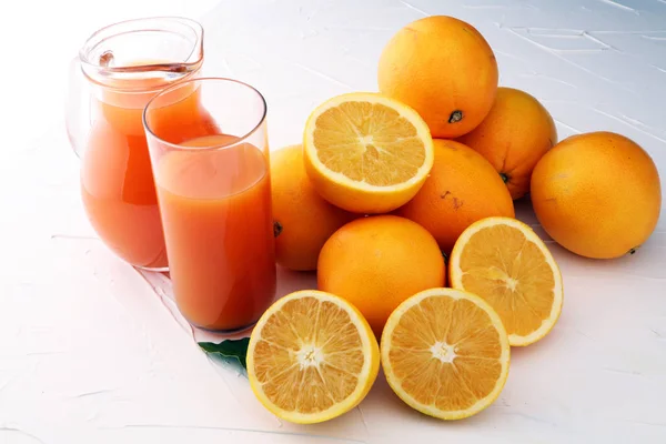 Bocal en verre de jus d'orange frais avec des fruits frais sur table blanche — Photo