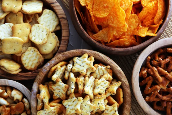 Słone przekąski. Precle, chipsy, krakersy w drewniane miski — Zdjęcie stockowe