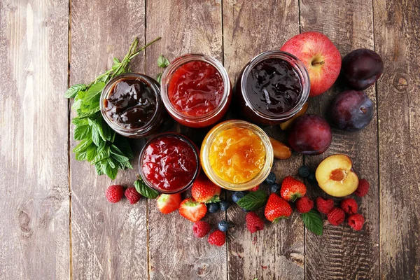 Assortment of jams, seasonal berries, plums, mint and fruits. — Stock Photo, Image