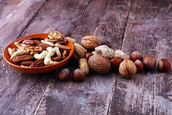 bowl with mixed nuts on wooden background. Healthy food and snac