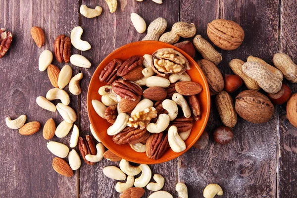bowl with mixed nuts on wooden background. Healthy food and snac