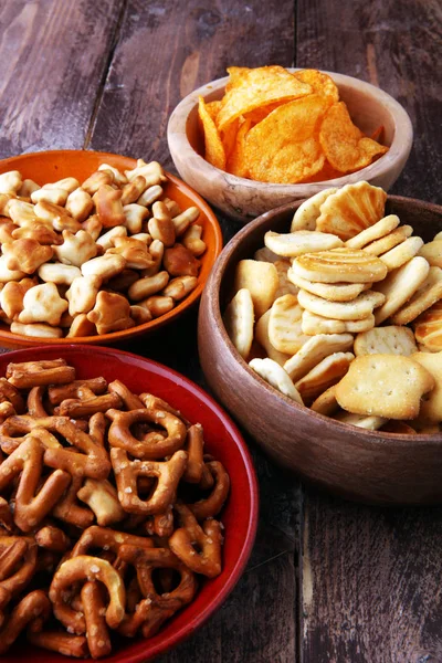 Petiscos salgados. Pretzels, batatas fritas, biscoitos em tigelas de madeira . — Fotografia de Stock