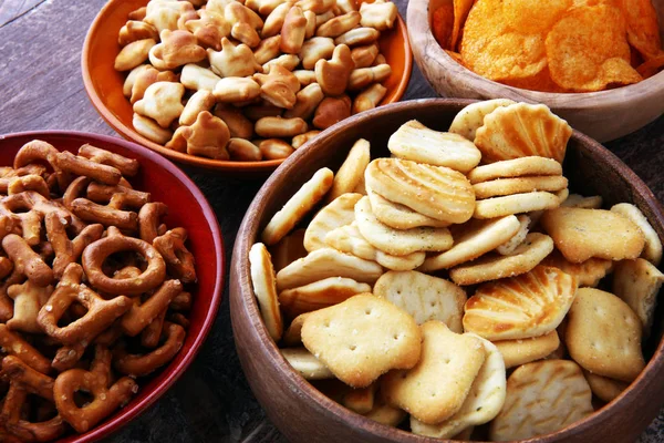Salty snacks. Pretzels, chips, crackers in wooden bowls. — Stock Photo, Image