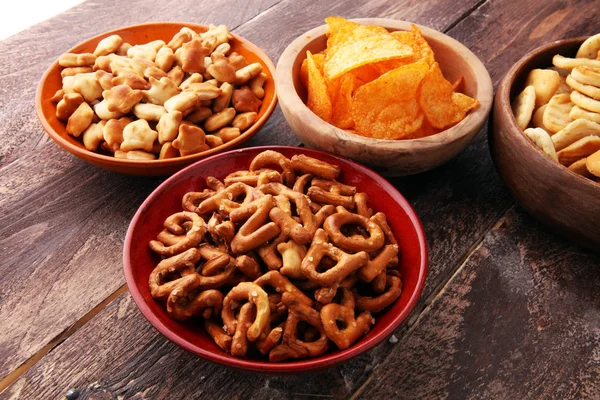 Salty snacks. Pretzels, chips, crackers in wooden bowls. — Stock Photo, Image