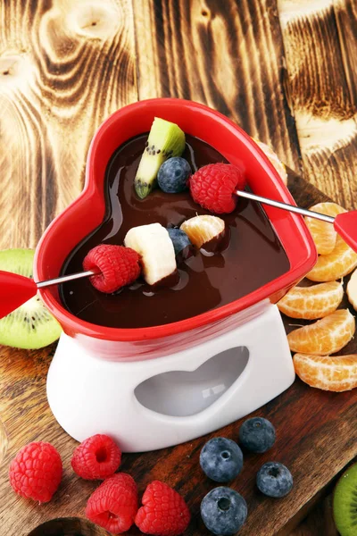 Chocolade fondue met fruit assortiment op houten snijplank. — Stockfoto